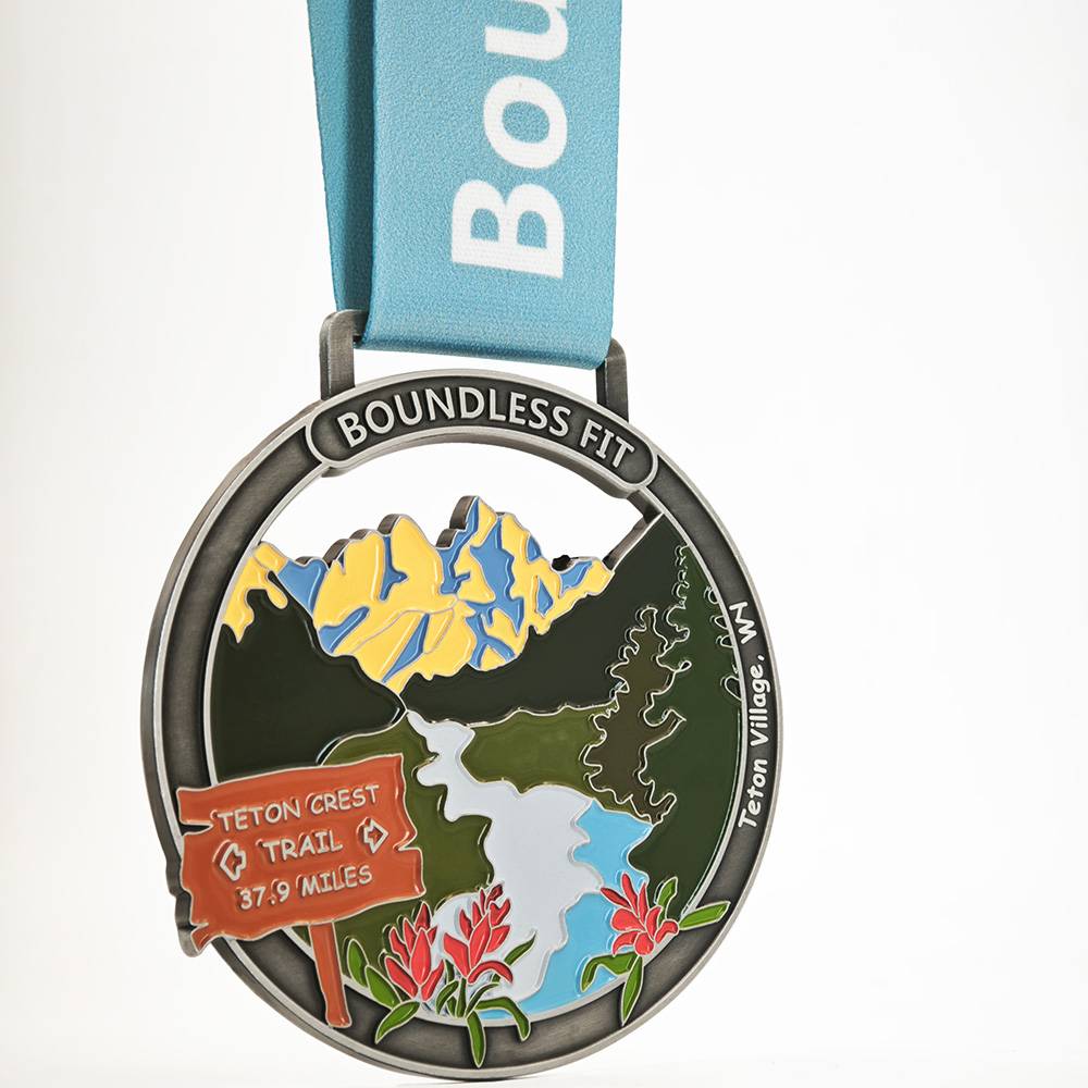 Teton Crest Finisher's Medal with engraved mountain vistas and a light blue ribbon